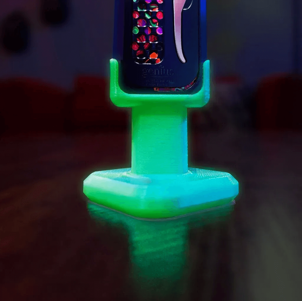 Genius “Lit” Stand glowing green in low light – glow-in-the-dark display stand – display and function highlighted.