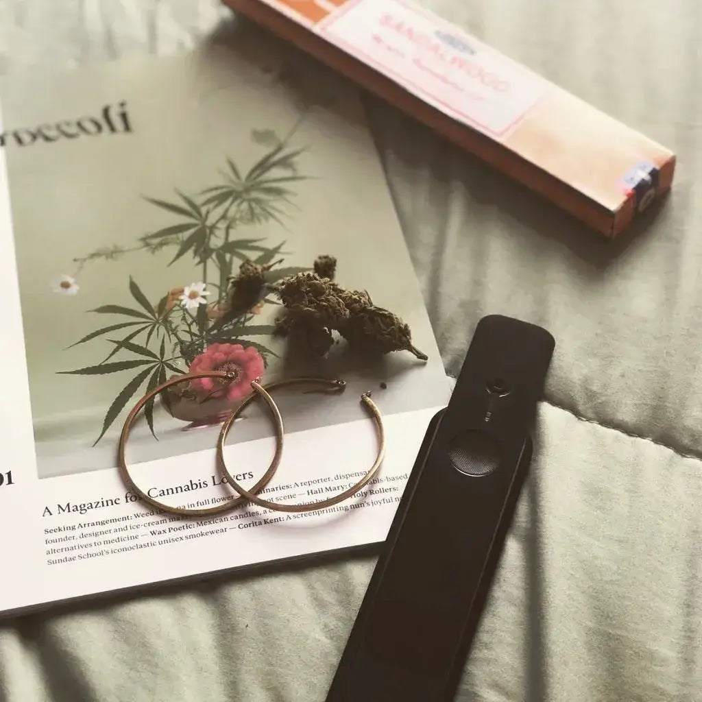 Genius Pipe – TOP Secret Stealth edition on bed near earrings – lifestyle photo.